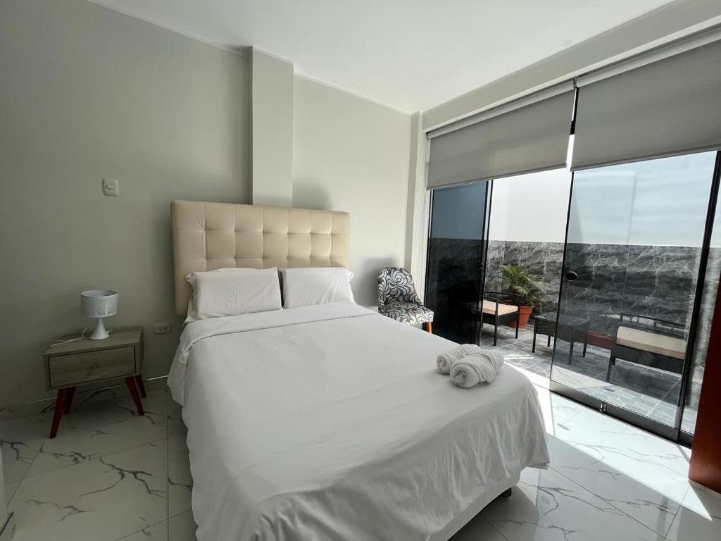 帕拉卡斯Makai - Nayarak Paracas的卧室设有一张白色大床和大窗户