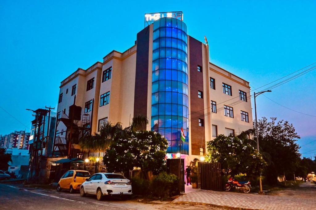 勒克瑙Hotel The Leaf - Gomti Nagar Lucknow的一座高大的建筑,前面有汽车停放