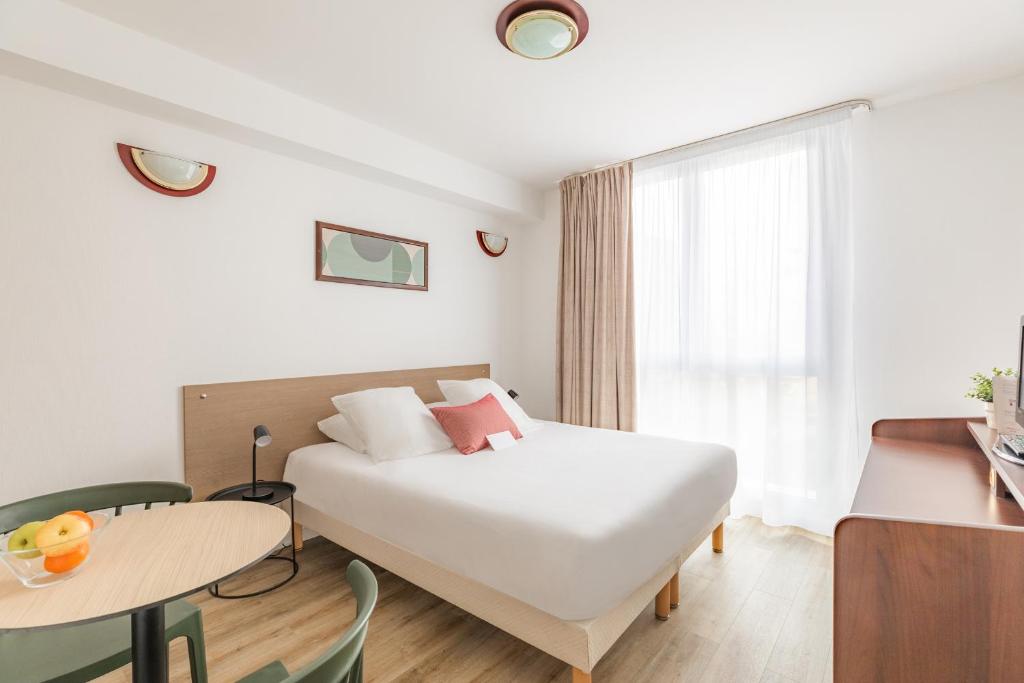 布雷斯特Appart'City Confort Brest的酒店客房设有床、桌子和窗户。
