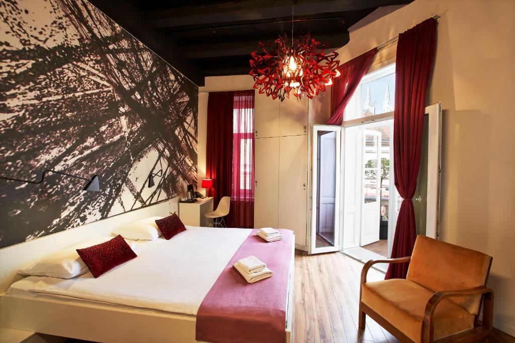 萨格勒布艺术风格酒店的卧室配有床、椅子和窗户。