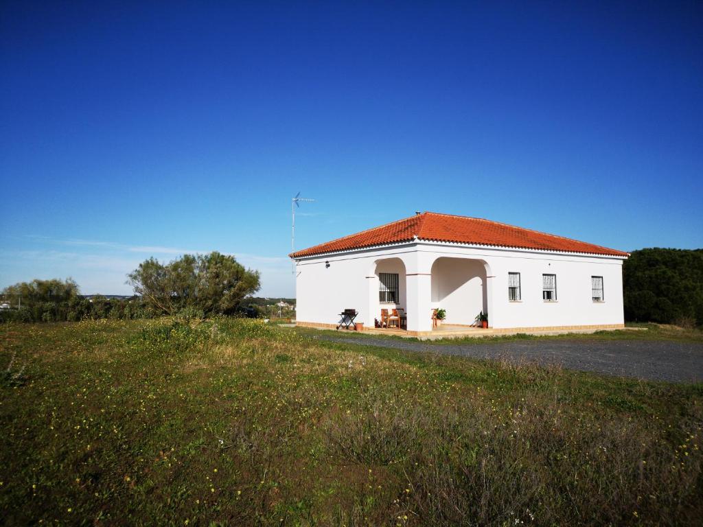 厄尔-汝姆披多Casa Rural Cerca de la Playa El Rompido的一座白色的建筑,在田野上有一个红色的屋顶