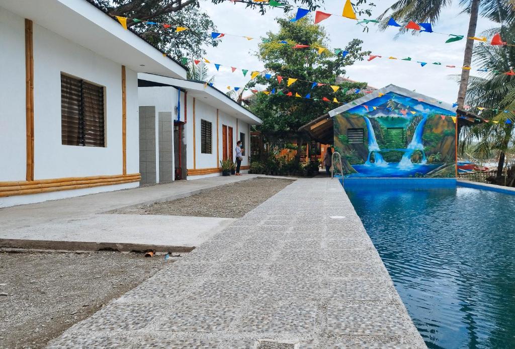 伊洛伊洛Casa Nena Hotel & Resort Iloilo by RedDoorz的一座游泳池,毗邻一座带旗帜的房屋和一座建筑