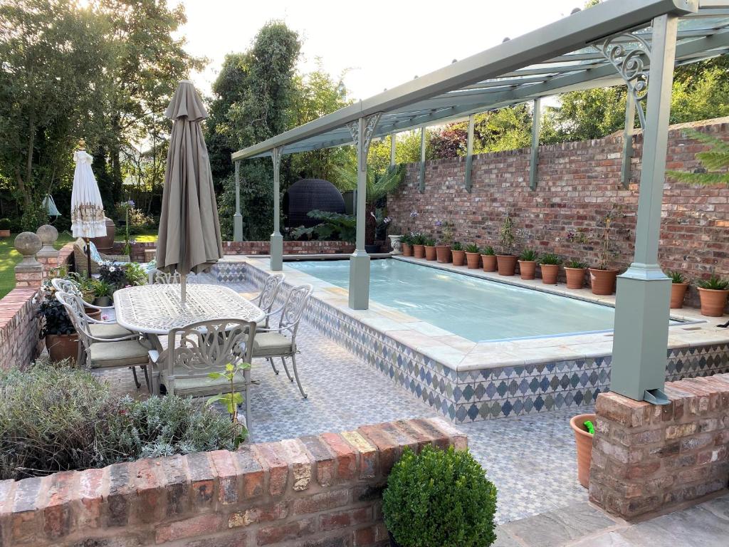 RobyLyndhurst - Victorian villa with heated pool的一个带桌子和遮阳伞的庭院和一个游泳池