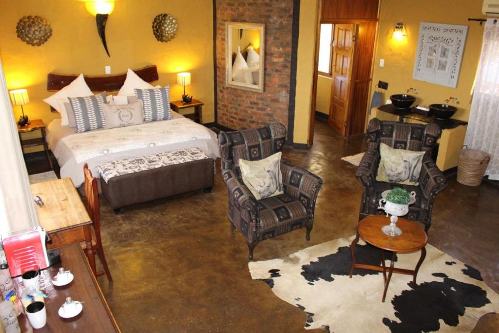 比勒陀利亚Ndlovu Lodge的一间卧室,卧室内配有一张床和椅子