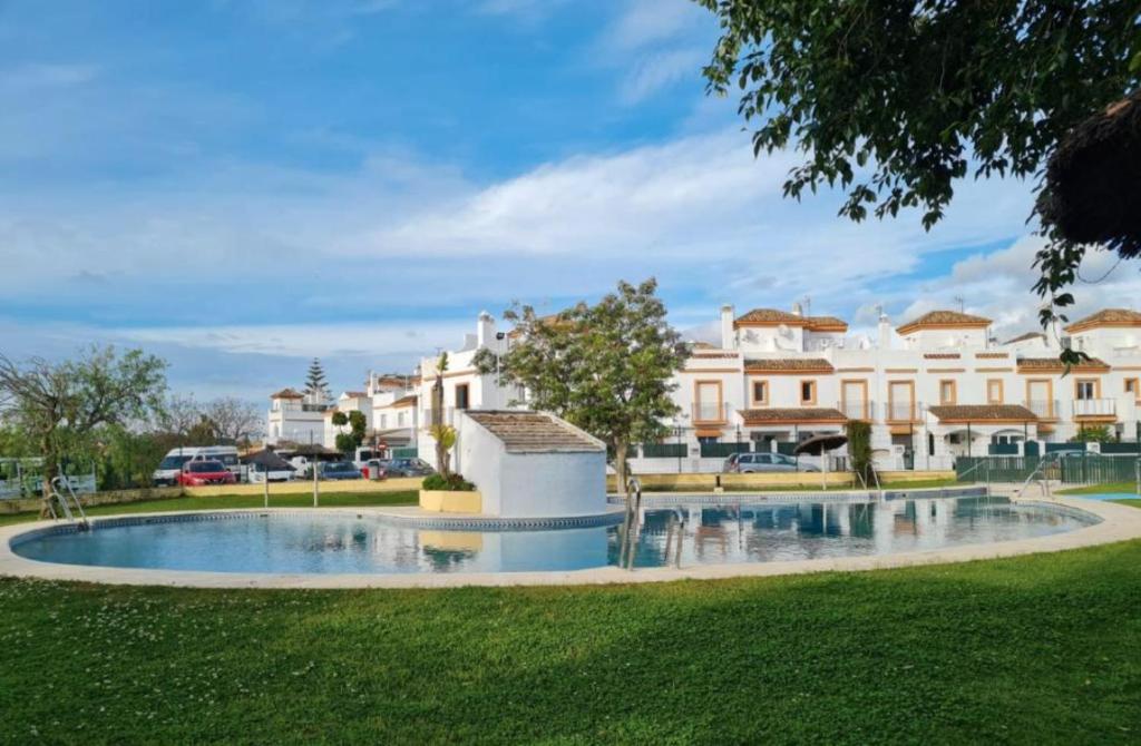 奇克拉纳－德拉弗龙特拉APARTAMENTO EN LOS GALLOS的一座公园内的大型游泳池,其建筑背景为: