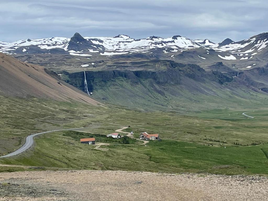 SnæfellsbærÖXL Snæfellsnes的山丘上的小房子,有积雪覆盖的山脉