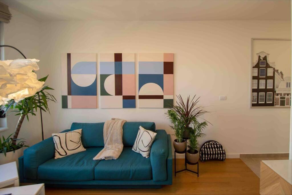 贝尔格莱德GARDOS BAUHAUS Apartment的客厅里一张蓝色的沙发,上面有绘画作品