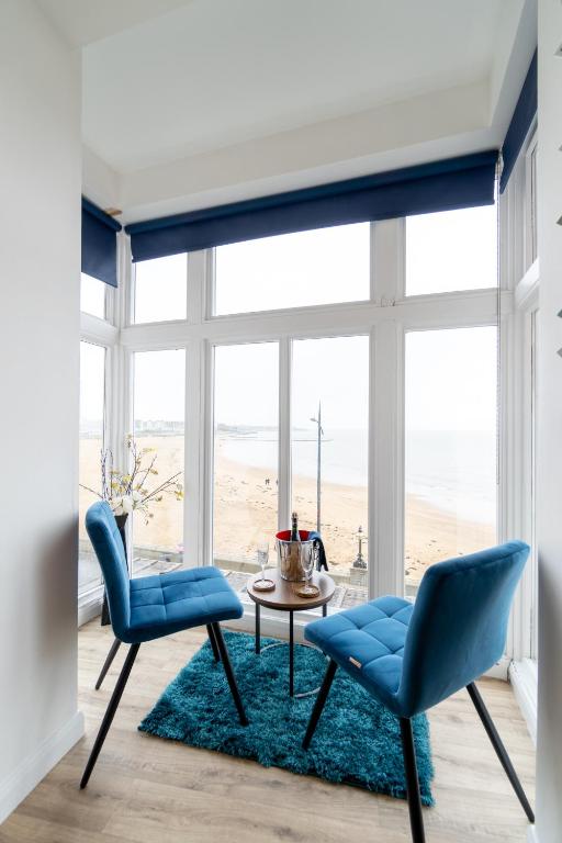 马盖特The Pearl Suite by Margate Suites的客厅配有蓝色椅子和一张桌子,享有海滩美景