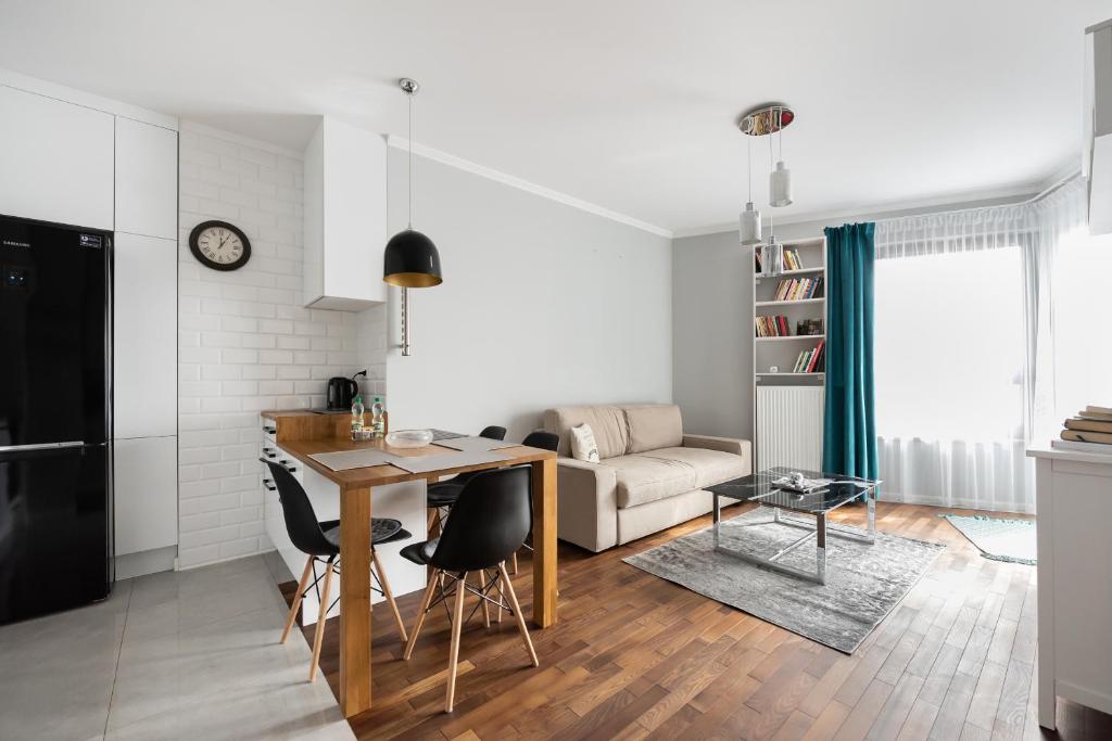 华沙Metro Płocka Exclusive Apartment的厨房以及带桌椅的起居室。