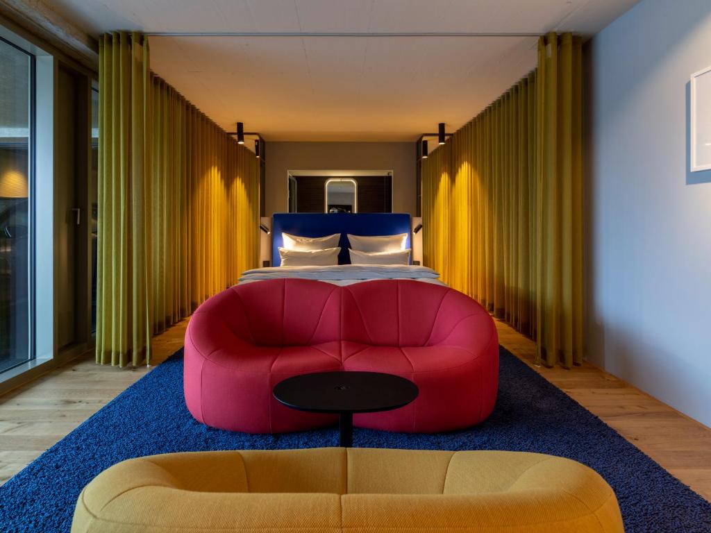 杜塞尔多夫b'mine hotel Düsseldorf的卧室在床前配有红色沙发