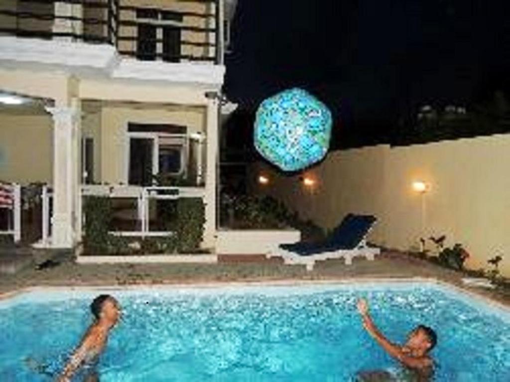 格兰贝伊2 bedrooms apartement at Grand Baie 400 m away from the beach with shared pool enclosed garden and wifi的两个男人晚上在游泳池游泳