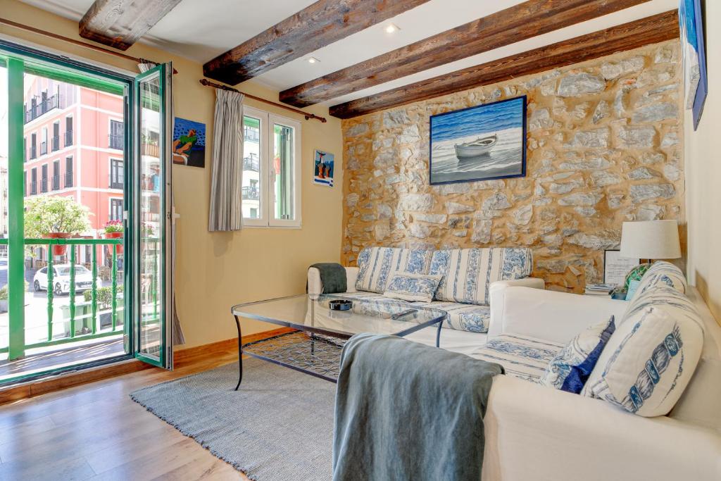 宏达瑞比亚Maravilloso apartamento en el corazón de Hondarribia的带沙发和石墙的客厅