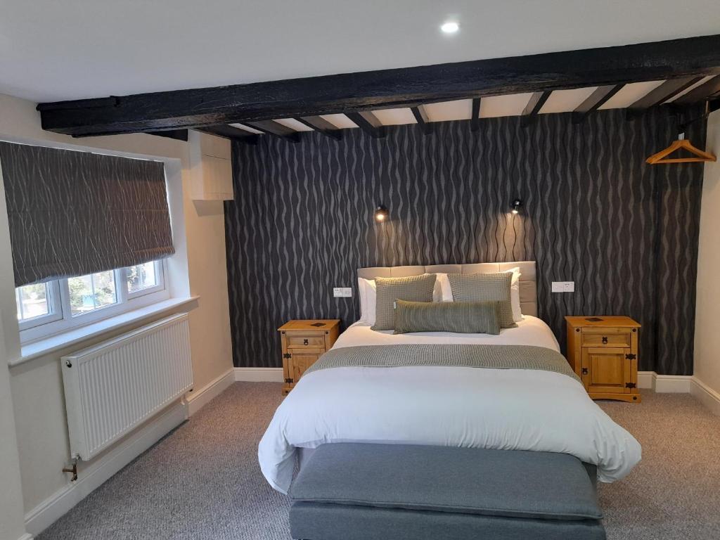 朗梅尔福德The George & Dragon Hotel的一间卧室设有一张大床和两个窗户。