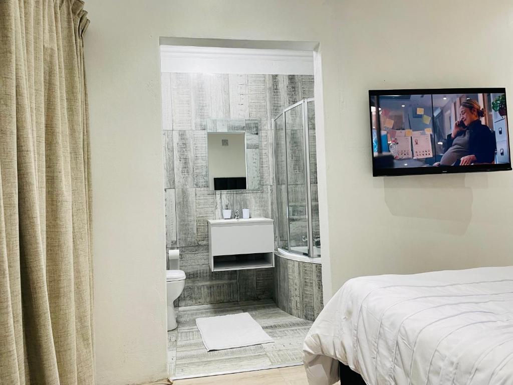 鲁德普特Stay In Carlazo - Unlimited WiFi, Solar backup的带淋浴的浴室和墙上的电视