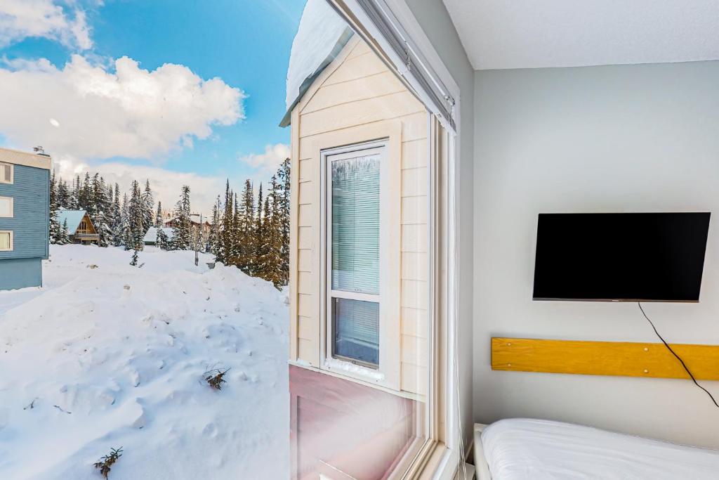 大白山Whitefoot Lodge 314的一间卧室设有窗户,配有电视和雪