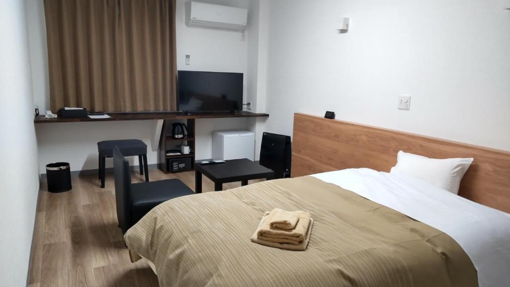 秩父市Basic Hotel Chichibu的配有一张床和一张书桌的酒店客房