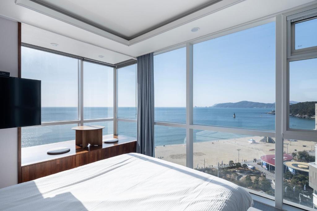釜山艾丽西亚精品酒店的一间卧室享有海滩美景