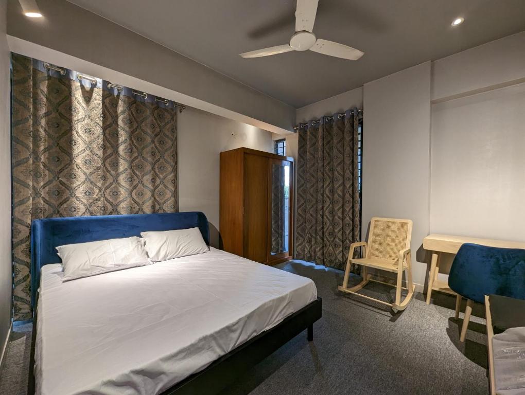 达卡GreyRooms的一间卧室配有一张床、一把椅子和吊扇