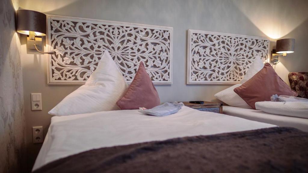 弗雷兴Hotel Haus Loewe的一间卧室配有带白色床单和粉红色枕头的床。