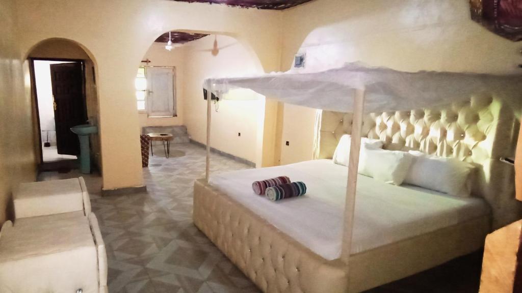 马林迪Baba Lao Hotel的卧室配有一张带遮阳伞的大型白色床
