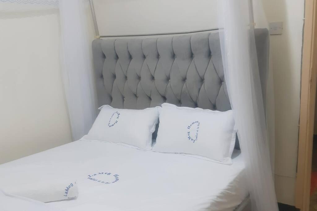 内罗毕LaMeg Homestay的一张白色的床,上面有两个白色的枕头