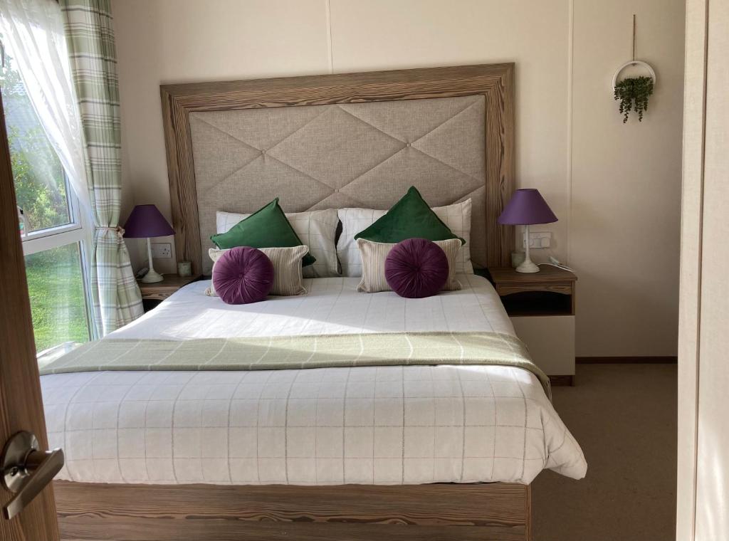 纽基BRANWOOD Acorn Caravan Holidays Newquay的一间卧室配有一张大床,提供紫色和绿色枕头
