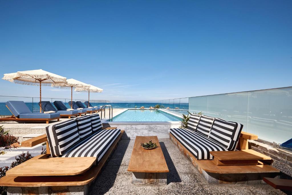 库基尼坎尼奥Rodo Seafront Villa with Heated private pool and jacuzzis by Volta Suites and Villas的一个带长椅和游泳池的庭院