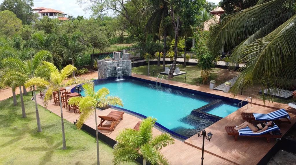 丹不拉White Land City Hotel的享有带椅子和棕榈树的游泳池的顶部景致