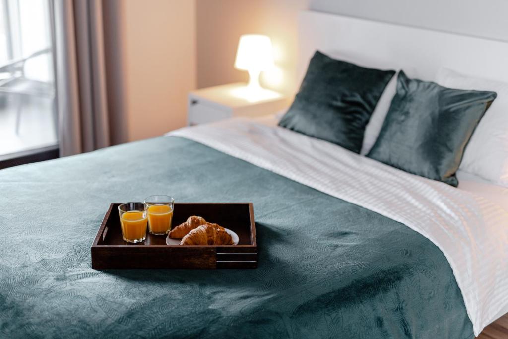 华沙City View Apartments的床上的面包盘和两杯橙汁