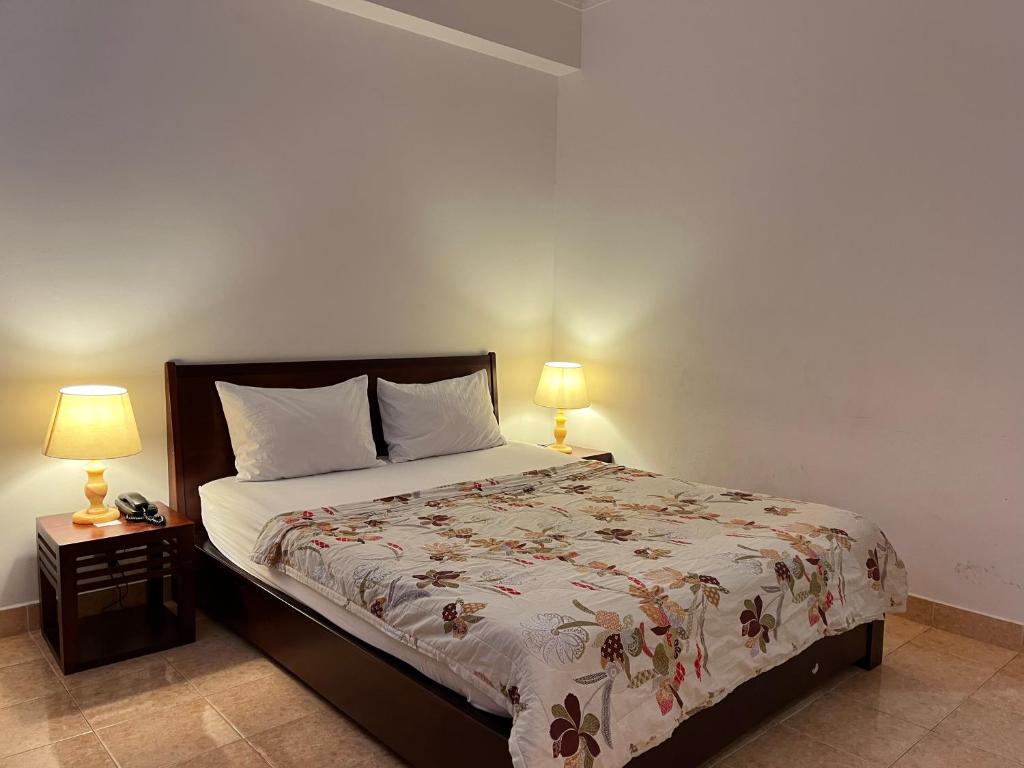 胡志明市Phung Long Hotel的一间卧室配有一张床和两张台灯。
