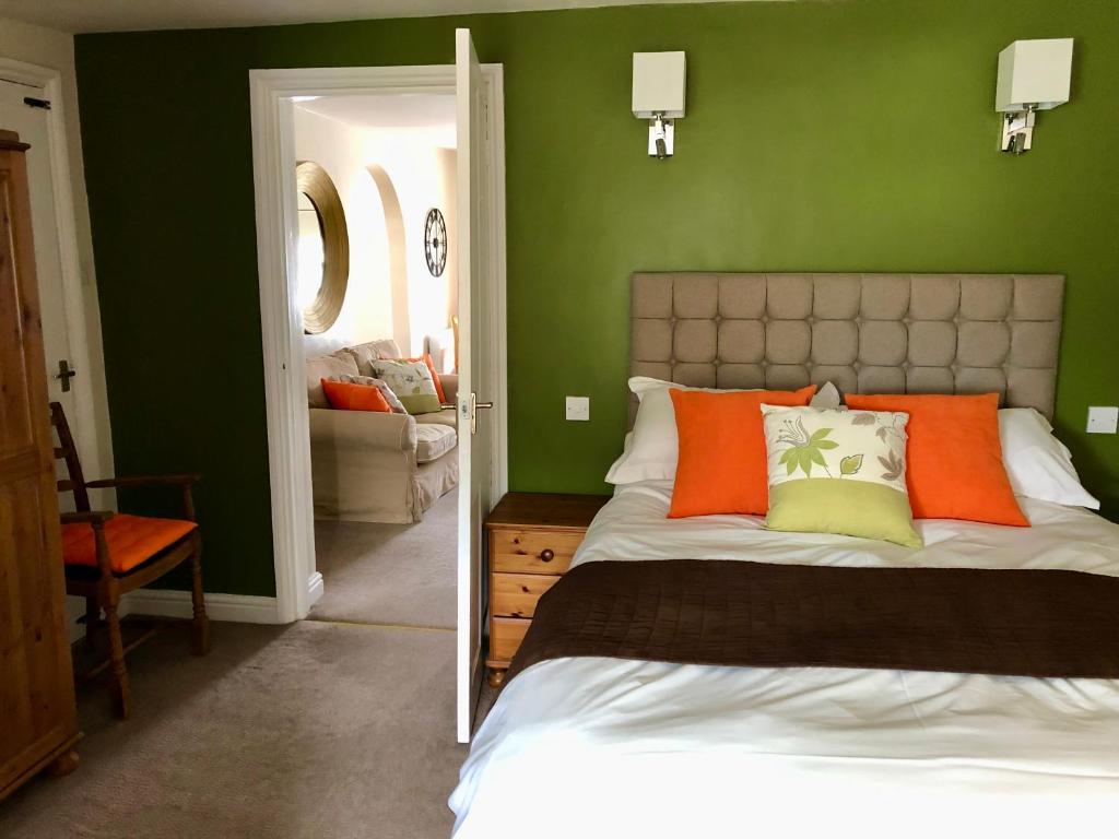 惠特比法凡公寓的一间卧室设有绿色的墙壁和一张带橙色枕头的床