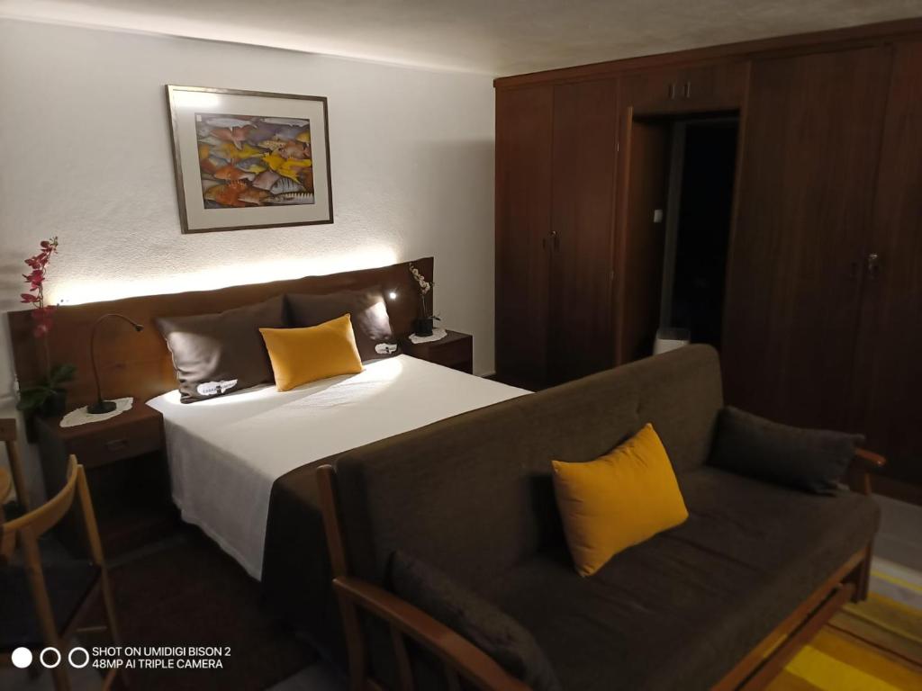 RibeirasCasa da Bicuda的一间卧室配有一张带黄色枕头的床和一张沙发。