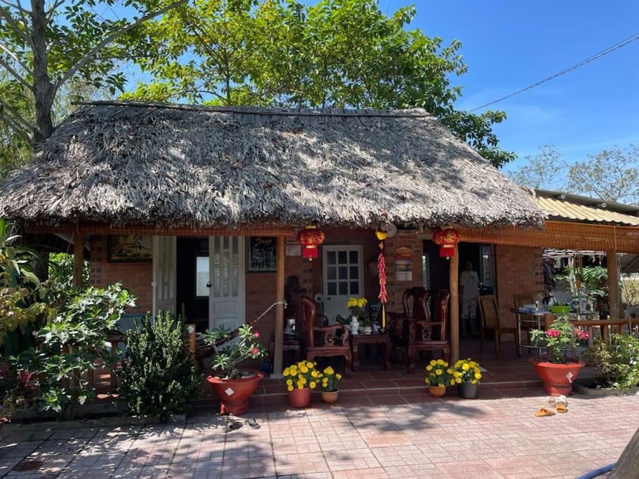 Tây NinhTy Phu Miet Vuon Homestay - Entire Bungalow的小屋设有茅草屋顶和庭院