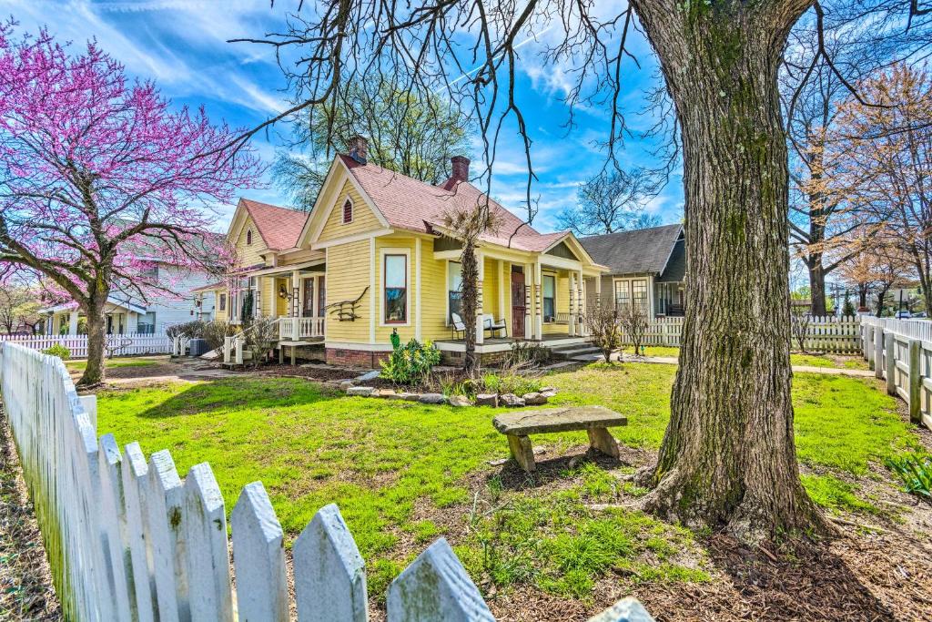 小石城Historic Home Near Downtown Little Rock!的围栏前有长凳的黄色房子