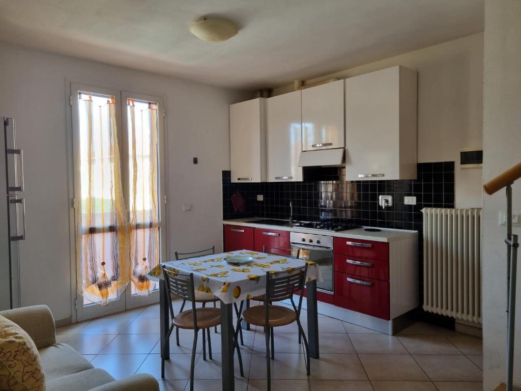 切齐纳码头Giacomo Home的厨房配有红色橱柜和桌椅