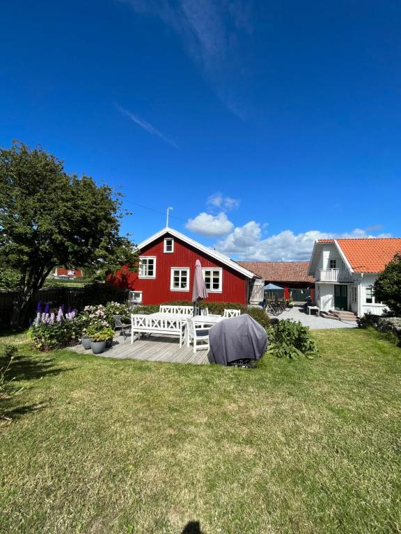 谢尔港Rovor och Rum Lägenhet Rännet的院子前的红色谷仓,有白色长凳