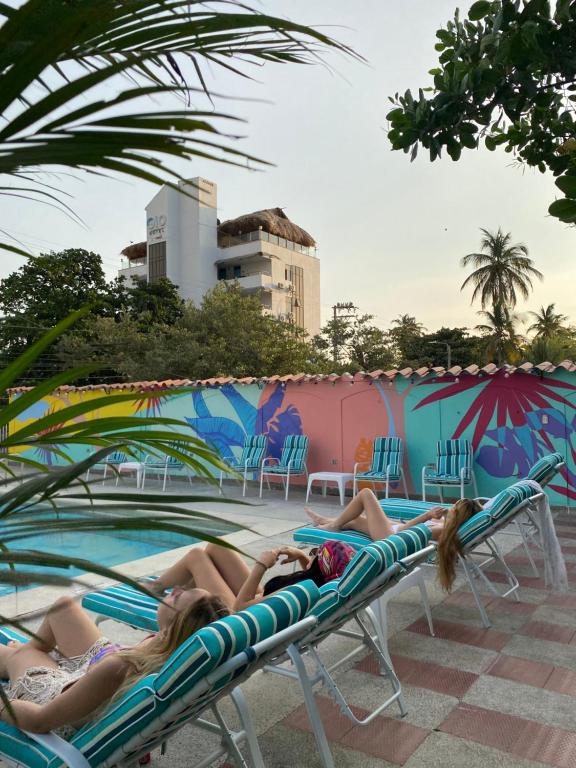 圣玛尔塔Los Veleros By StHoteles的两名妇女在游泳池畔的躺椅上躺着