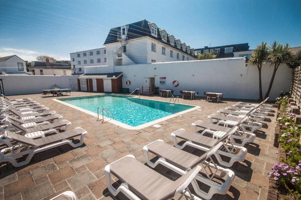 圣赫利尔泽西诺弗克酒店的一个带躺椅的游泳池和一间酒店