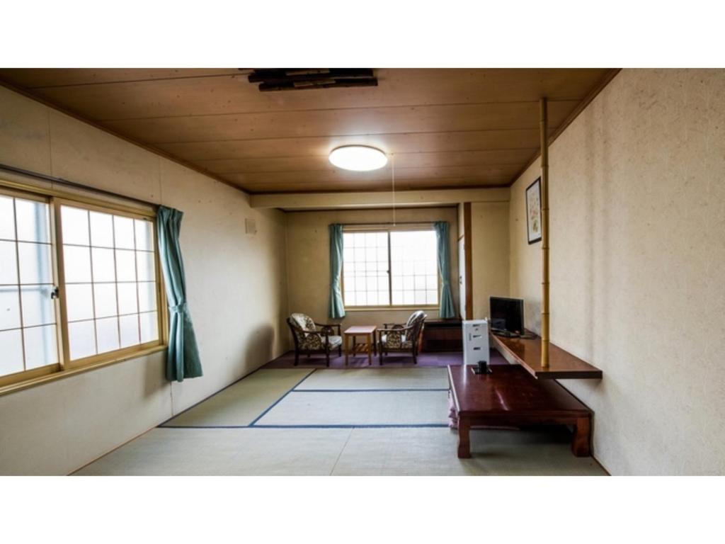 北见Onsen Hotel Tsutsujiso - Vacation STAY 03255v的客厅配有桌椅和窗户。
