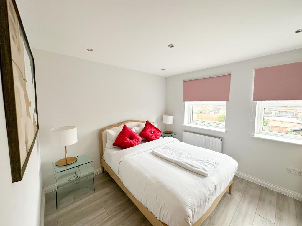 Hackbridge2b Seymour road的一间卧室配有一张带红色枕头的床