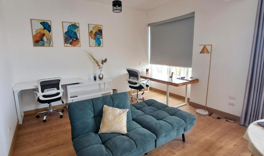 利马VK Loft - Apartamento en Miraflores的客厅配有蓝色的沙发和书桌