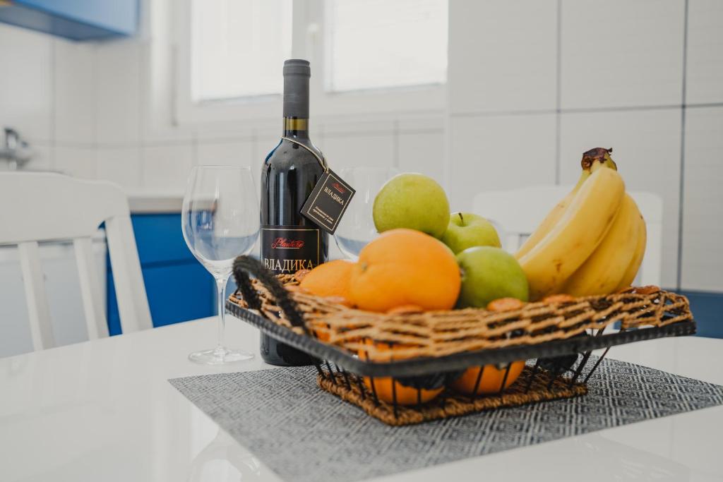 蒂瓦特Apartments Djukic的柜台上一篮水果和一瓶葡萄酒