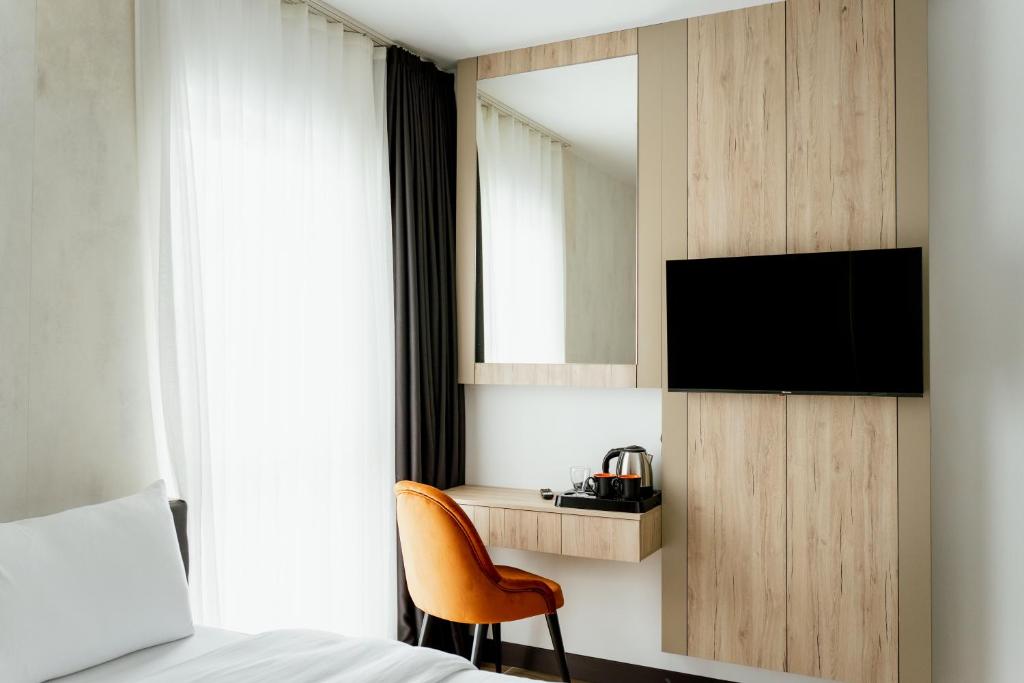 维也纳新城Lamede的一间卧室配有一张床、一台电视和一把椅子