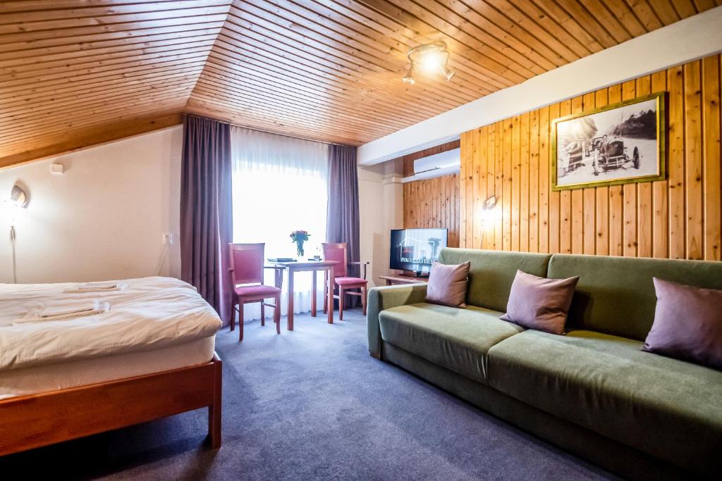 普列维扎Hotel Squash Centrum的酒店客房配有床、沙发和桌子。