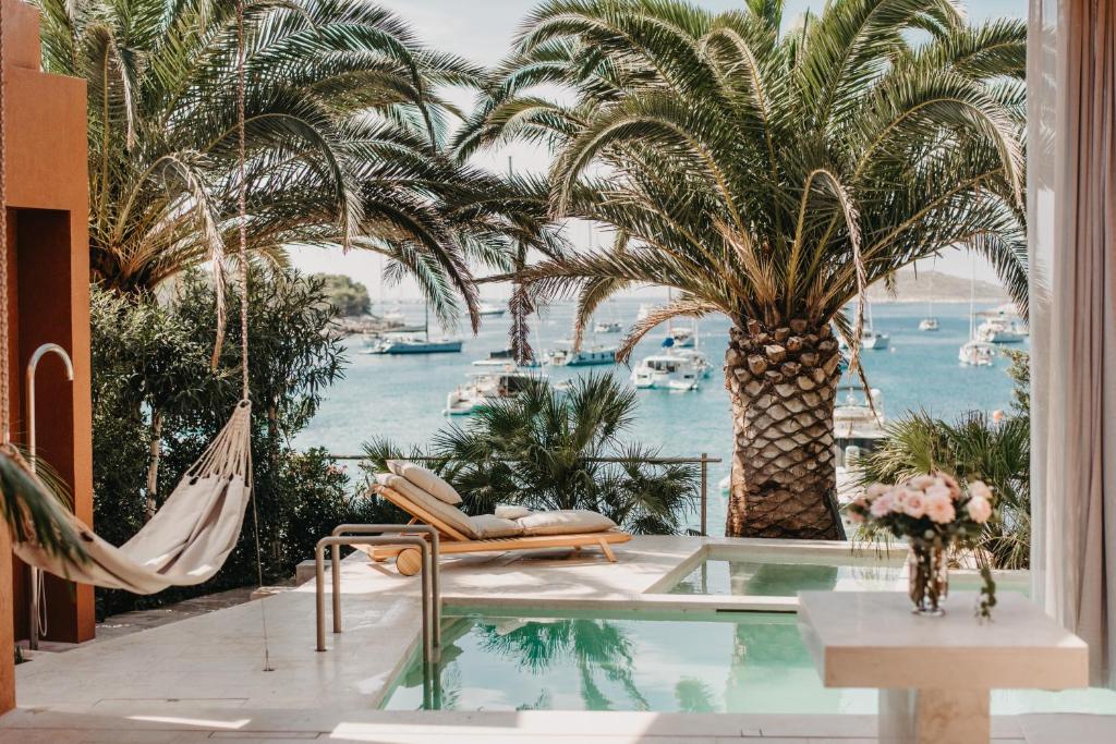 赫瓦尔Zori Timeless Hotel的一间设有吊床、棕榈树和游泳池的客房