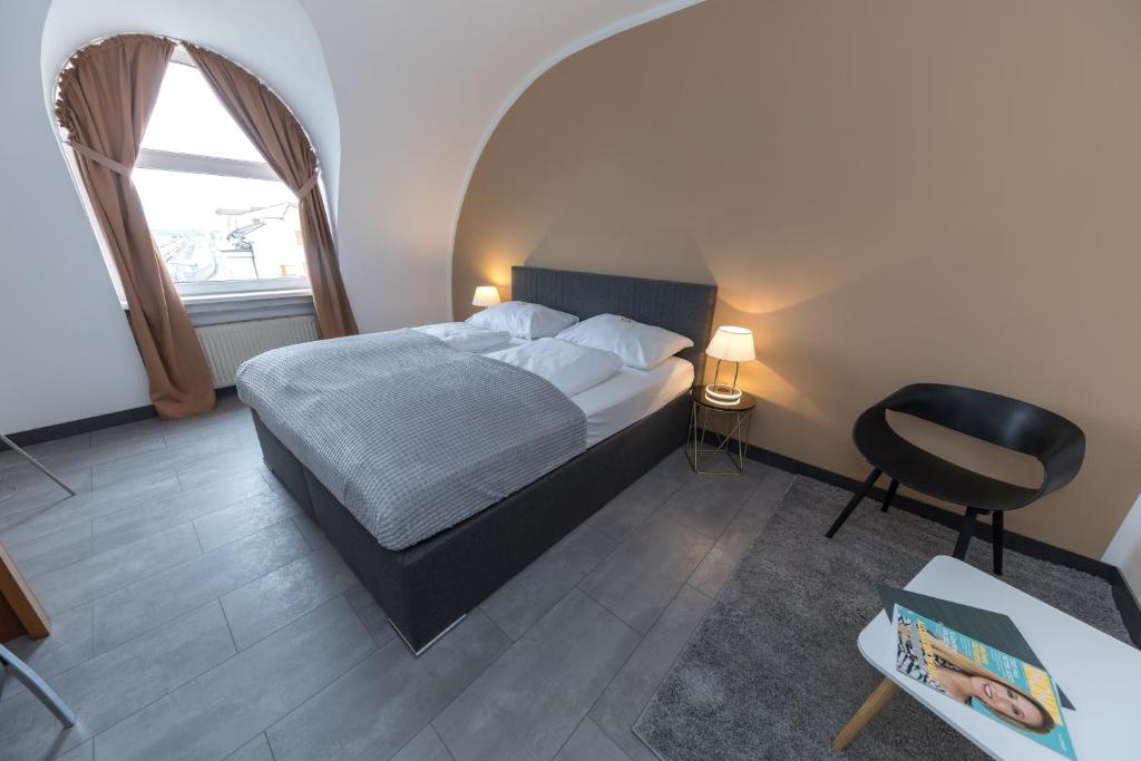 克拉根福Skycity Hotel Atrigon的卧室配有床、椅子和窗户。