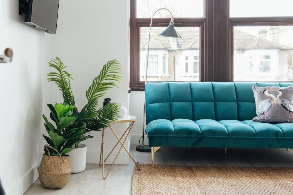 依尔福Modern 2 Bedroom Flat in Ilford, London的客厅里摆放着蓝色的沙发,上面种有植物