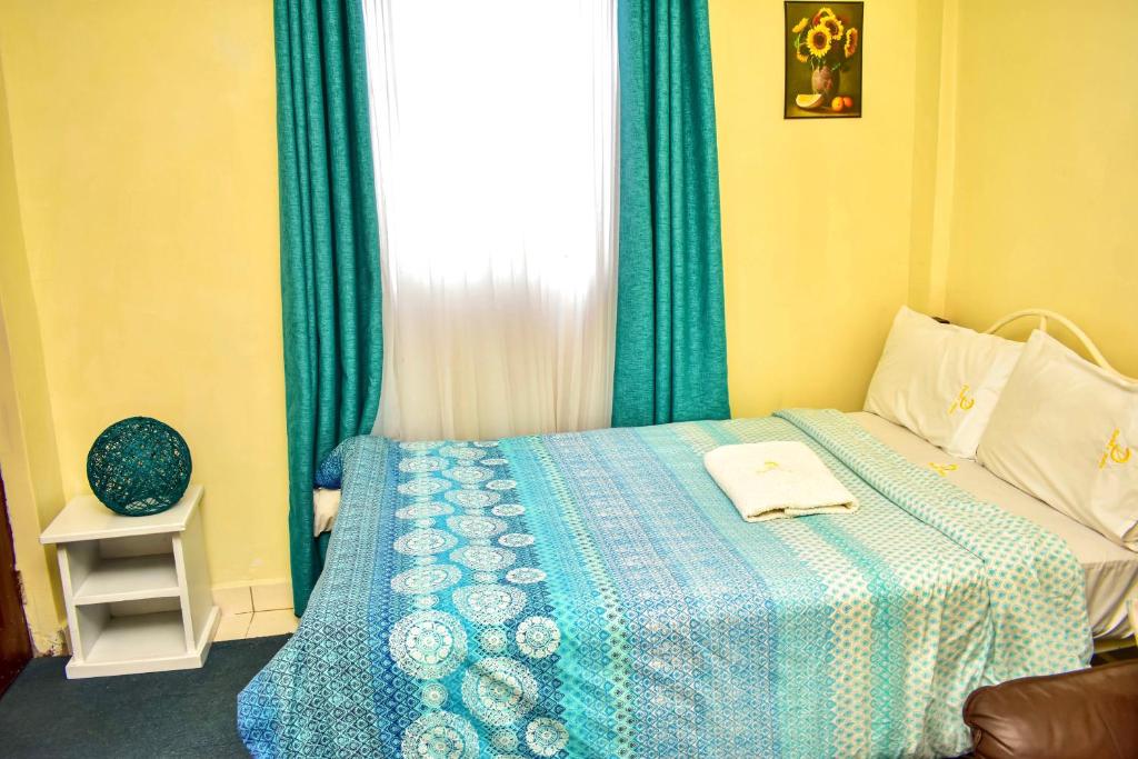 基苏木Classic Studio Milimani - Wi-Fi and Parking的一间卧室配有一张带蓝色毯子的床和窗户。