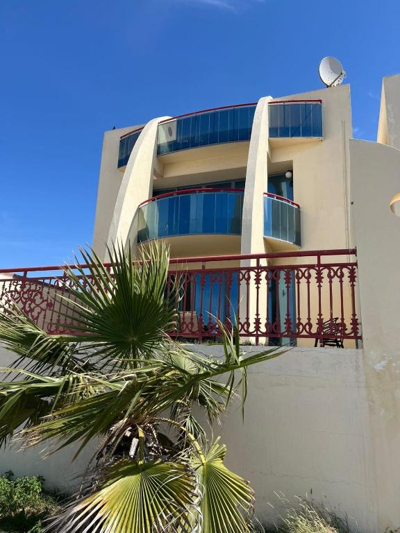 乌姆盖万5 bedroom relaxing villa with sea view的带阳台和棕榈树的建筑