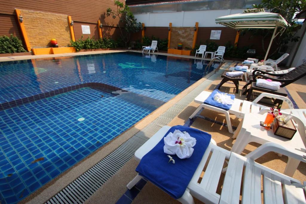乔木提恩海滩Valhalla Pattaya的一个带白色椅子的游泳池和一个蓝色的游泳池